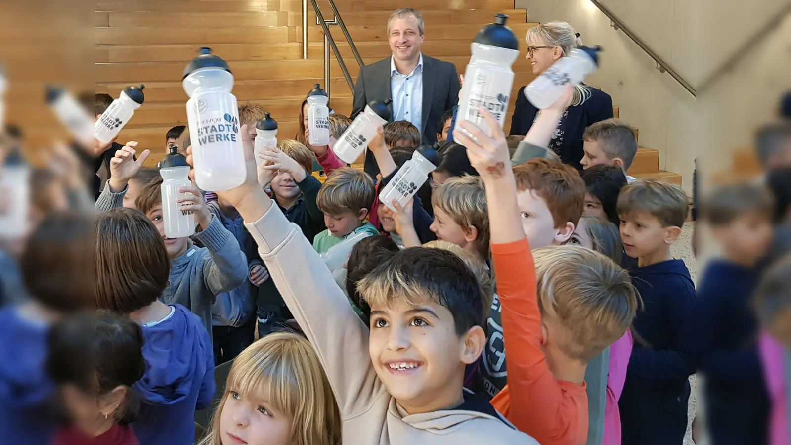 Die Erstklässler der Grundschule am SteinPark und Schulleiterin Sabine Jackermaier freuten sich über die geschenkten Trinkflaschen, die Dominik Schwegler, Geschäftsführer Freisinger Stadtwerke, mitgebracht hatte. (Foto: Freisinger Stadtwerke)