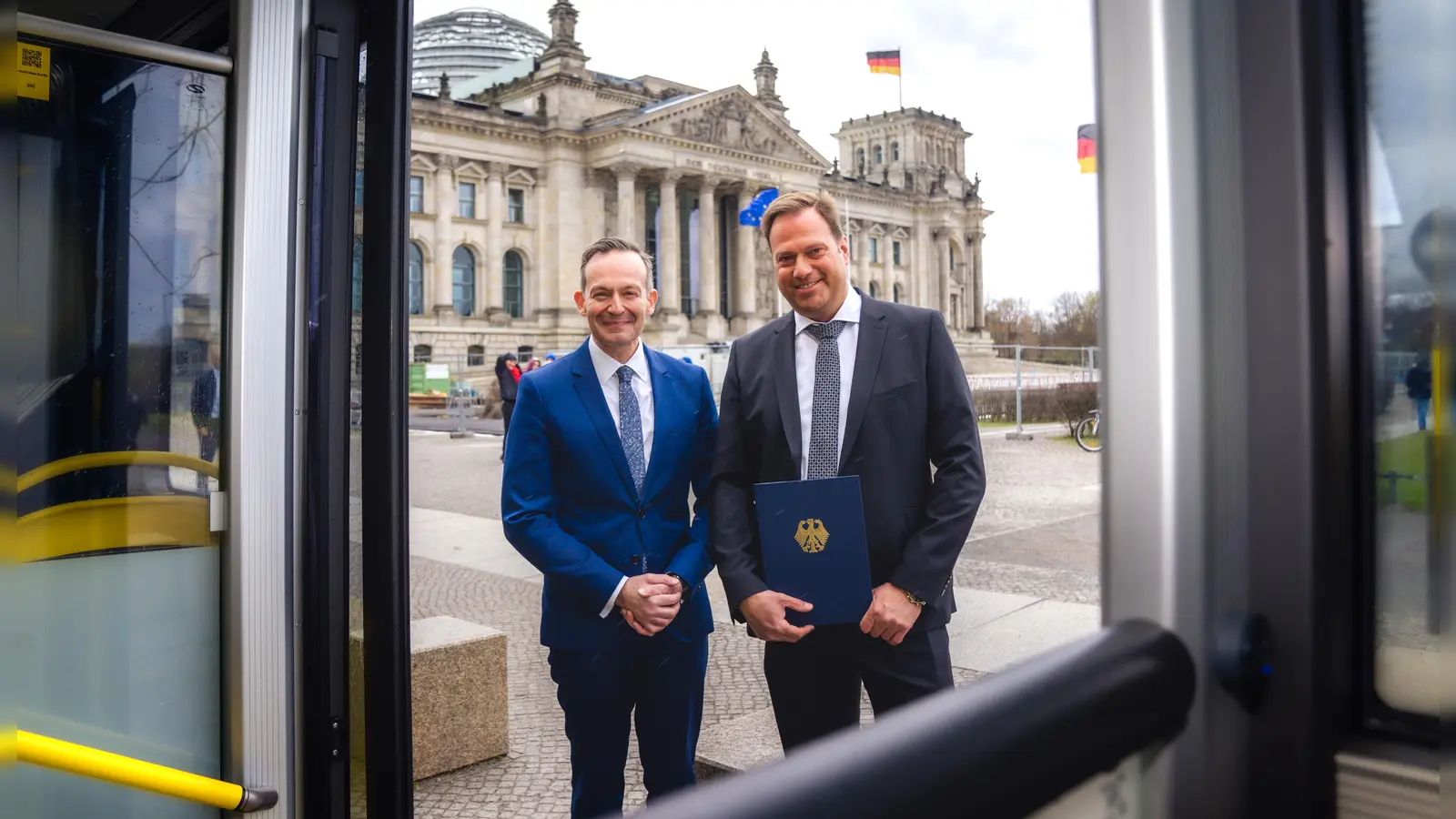Förderbescheid übergeben: Bundesverkehrsminister Volker Wissing (links) und der Geschäftsführer der AeroGround Flughafen München GmbH, Helmut Ehrnstraßer, vor dem Reichstag in Berlin. (Foto: Basti Wöhl/BMDV)