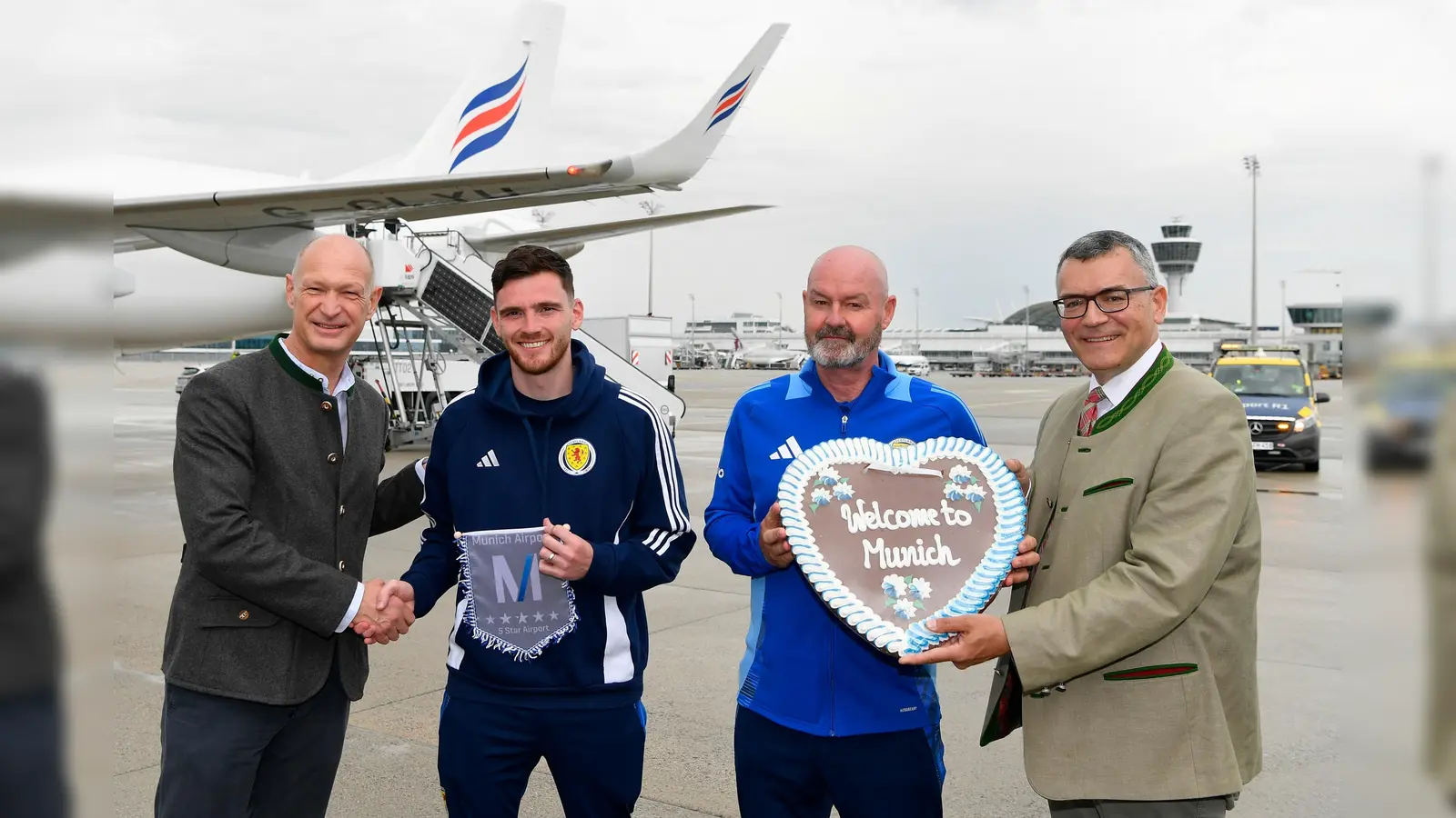 Jost Lammers, Vorsitzenderder Geschäftsführung der Flughafen München GmbH, Teamcaptain Andy Robertson, Trainer Steve Clarke und Staatsminister Dr. Florian Herrmann (v.l.). (Foto:  Flughafen München GmbH)