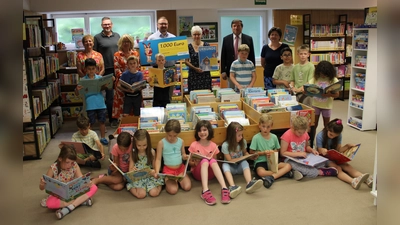 Die Klasse 1a der Grundschule am Ludwig-Simmet-Anger kommt regelmäßig in die Pfarrbücherei und profitiert von der Unterstützung, die Tobias Brockel (2.von links) an Oberbürgerbürgermeister Max Gotz (2. von rechts) und Bücherei-Leiterin Renate Paukner-Fill (Mitte) überreichte. (Foto: Stadt Erding)