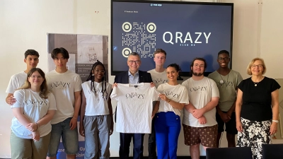 Staatsminister Dr. Florian Herrmann (Mitte) unterstützt das Juniorunternehmen QRazy. Oberstudiendirektorin und Schulleiterin Andrea Bliese (rechts) ist stolz auf ihre Jungunternehmerinnen und Jungunternehmer.  (Foto: Camerloher Gymnasium)