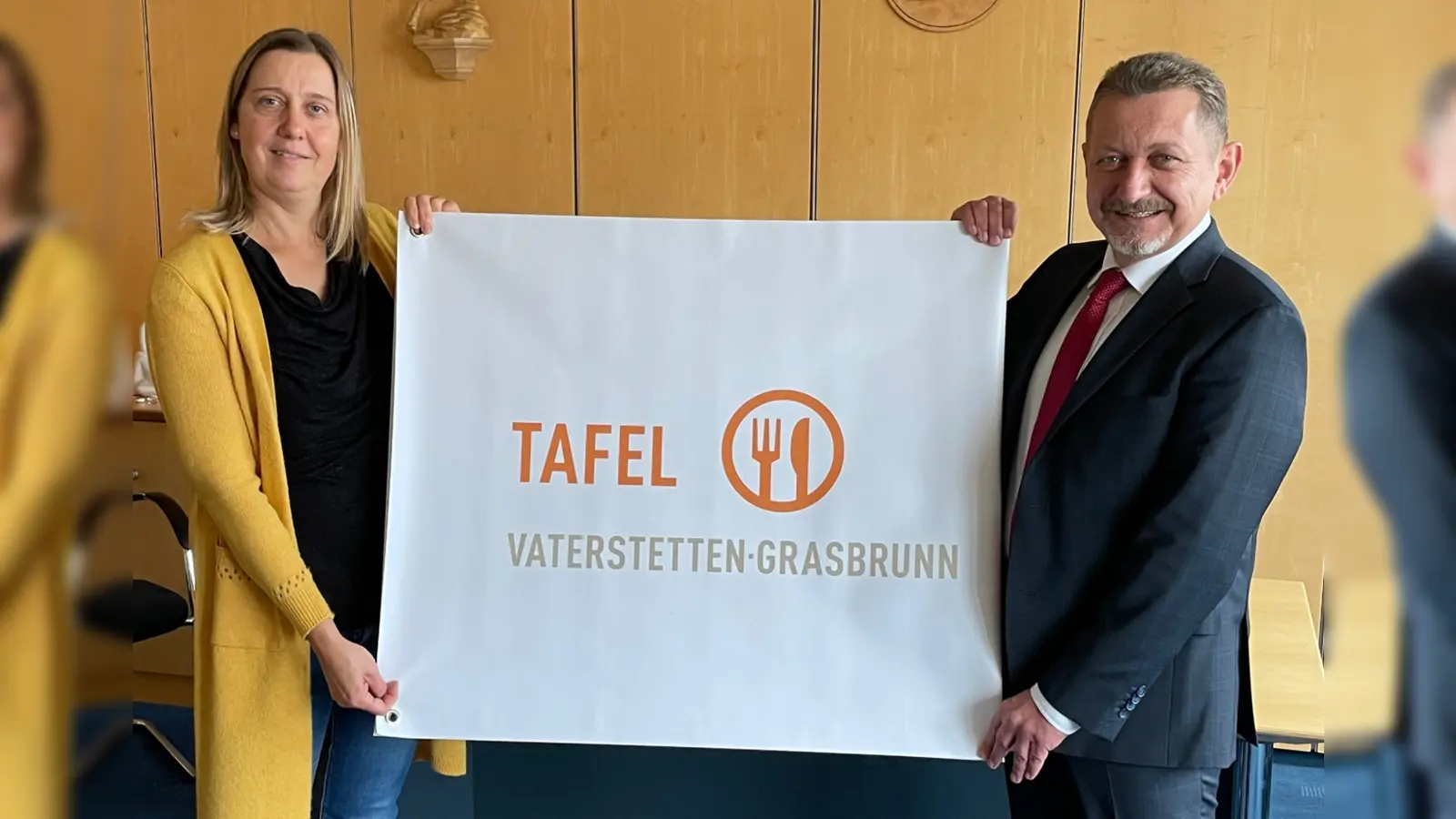nbh-Mitarbeiterin Julia Haigis und Grasbrunns Bürgermeister Klaus Korneder freuen sich über das neue Banner "Tafel Vaterstetten-Grasbrunn". (Foto: Nachbarschaftshilfe)