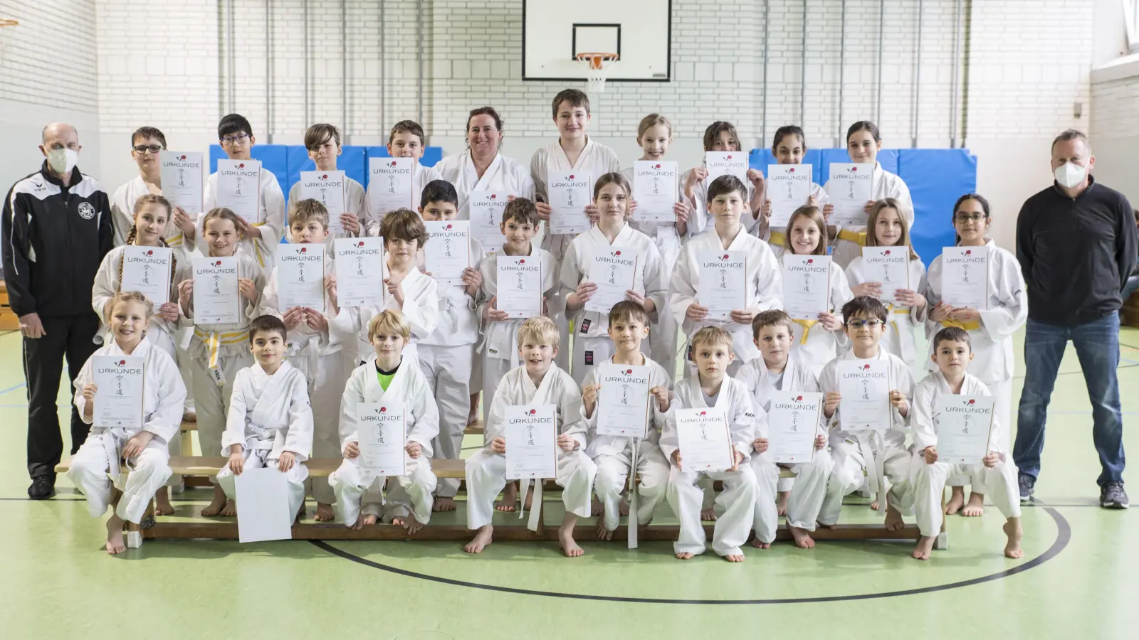 Endlich wieder Gürtelprüfung: 30 glückliche Karateka und ihre Prüfer Christian Martin (li.) und Dr. Dietmar Wagner (re.). (Foto: Marco Fuekelsberger)